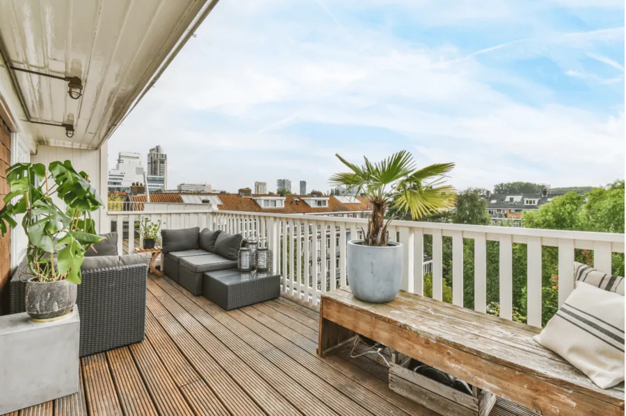 Dachterrasse mit Loungemöbeln, Pflanzkübeln und weißem Geländer.