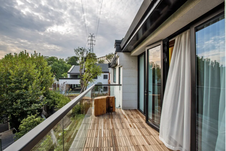 Balkon mit Glasgeländer und Blick auf Bäume und Nachbarhäuser.