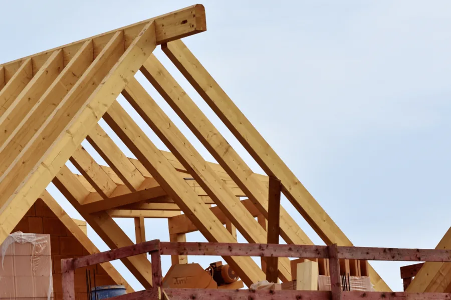 Holzdachstuhl mit Sparren und Kehlbalken vor blauem Himmel.