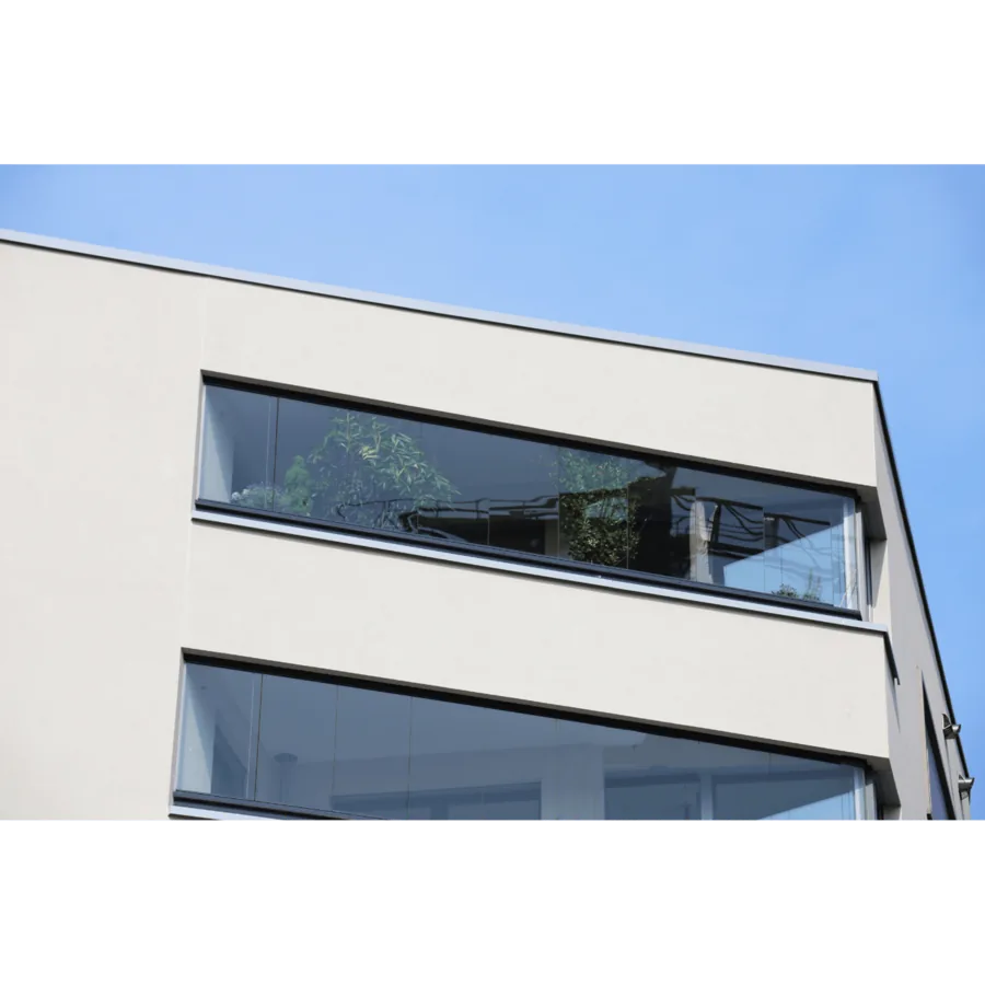Moderne Wohnhausfassade mit großen Glasfronten und Spiegelungen des Himmels und Bäumen.