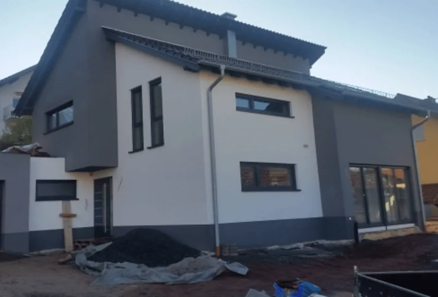 Wohnhaus mit neuen Fenstern und Türen, davor noch unbefestigtes Gelände.